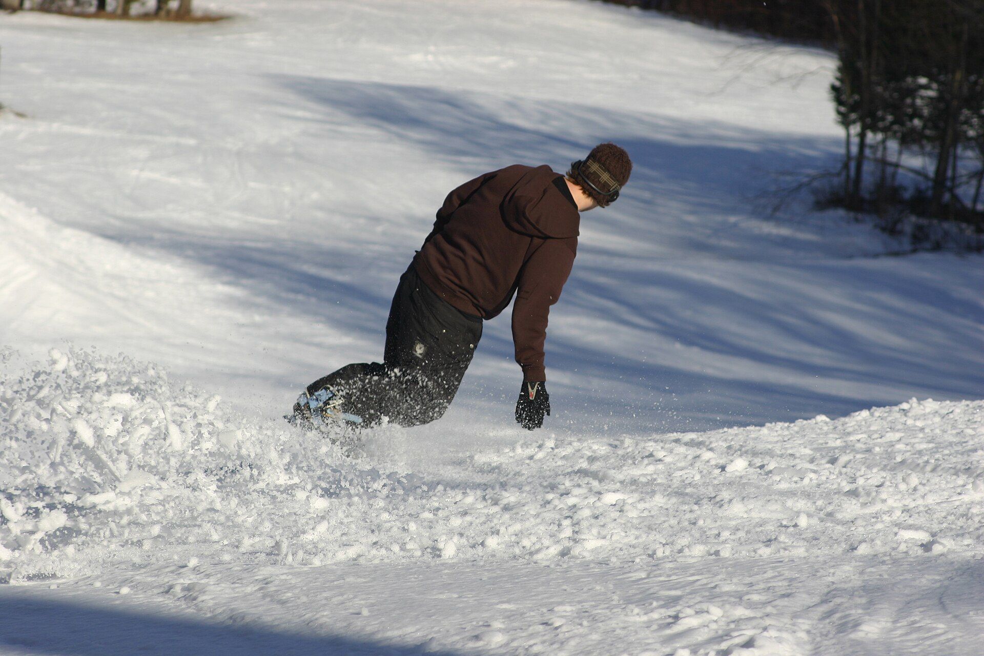 A snowboarder leaning into a carved turn on a groomed slope.