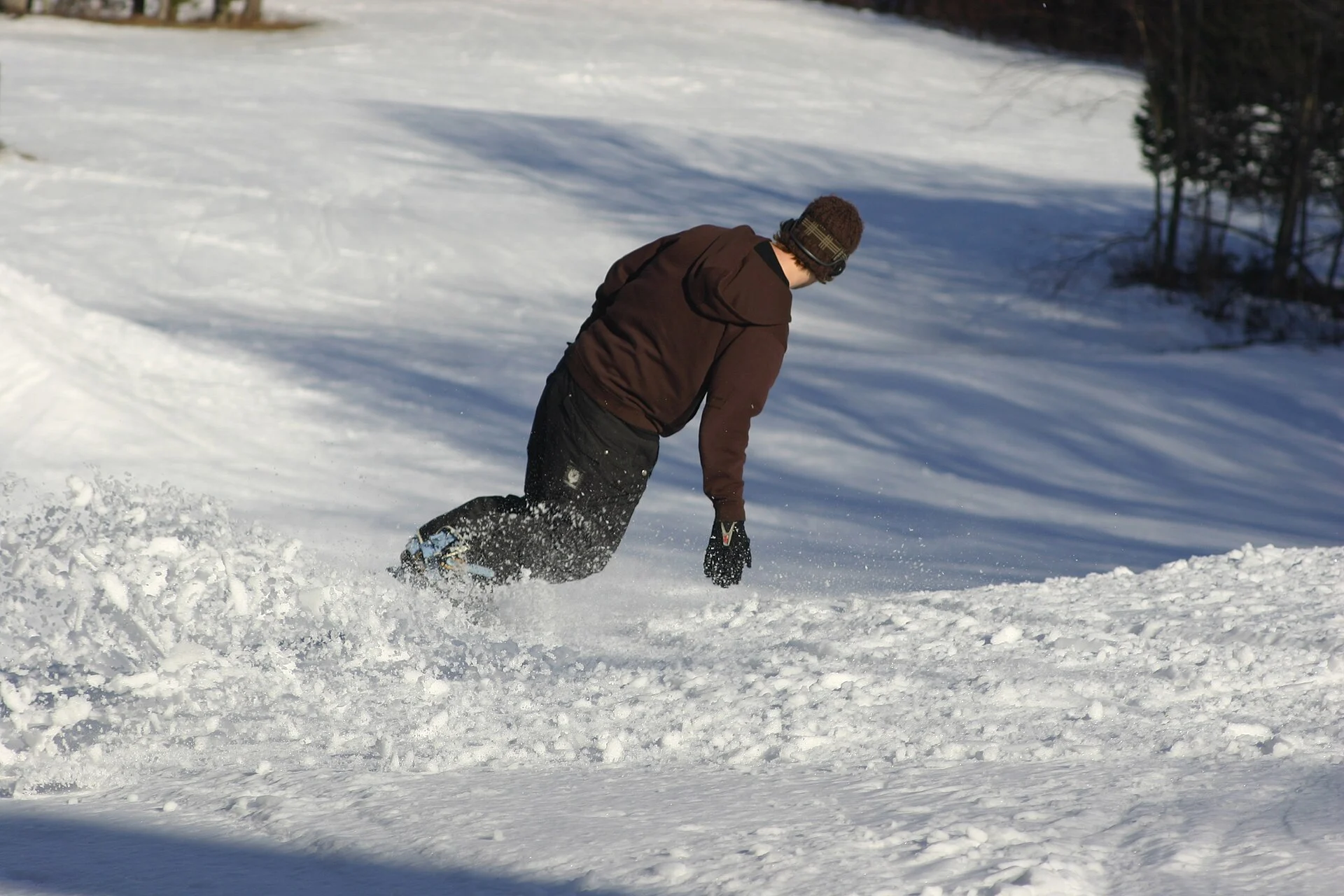 A snowboarder leaning into a carved turn on a groomed slope.