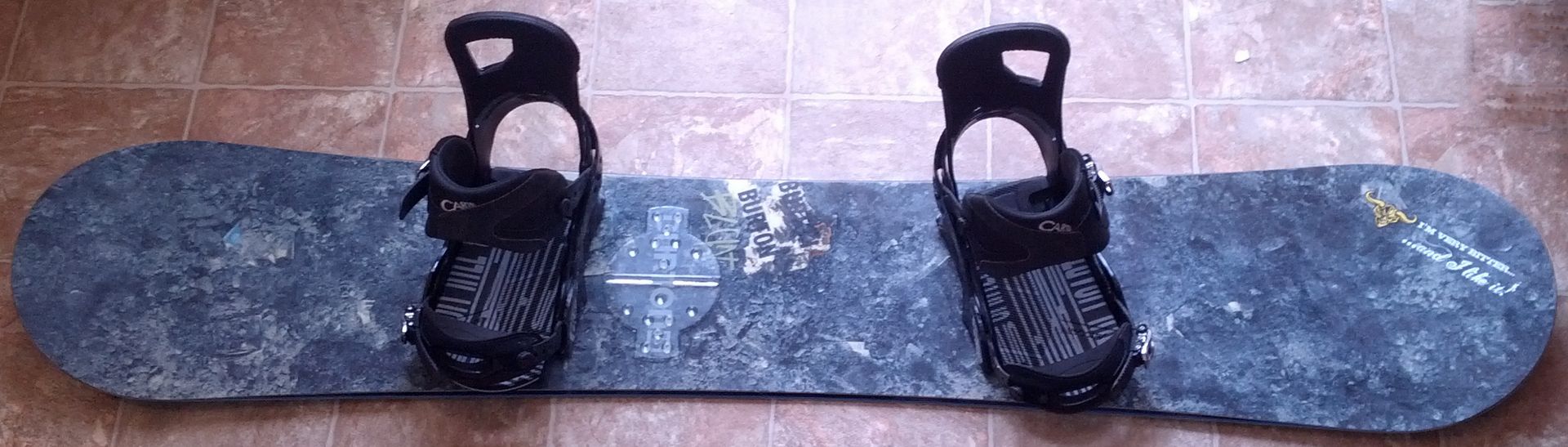 Snowboard laid flat with two strap bindings mounted in a duck stance.